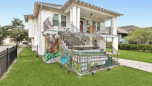 A two-story house with a front porch, a staircase, and a mural on the front steps. - Spacious 3-Bedroom Uptown House – Steps to Streetcar & Downtown (New Orleans)