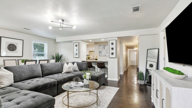 A modern living room with a sectional sofa, a coffee table, and a TV on a cabinet. - Spacious 3-Bedroom Uptown House – Steps to Streetcar & Downtown (New Orleans)