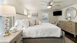 A bedroom with a bed, bedside table, lamp, dresser, mirror, TV, and ceiling fan. - Spacious 3-Bedroom Uptown House – Steps to Streetcar & Downtown (New Orleans)