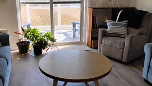 A living room with a round wooden table, a sofa, a chair, and a bookshelf. - Quiet Waterfront Getaway Private Escape 1BR Apt Retreat with Optional Boat Dock (Stevensville)