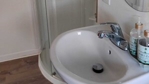 A bathroom with a white sink, a glass shower enclosure, and a mirror. - Quiet Waterfront Getaway Private Escape 1BR Apt Retreat with Optional Boat Dock (Stevensville)