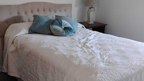 A bed with a tufted headboard, a white quilt, and two pillows. - Quiet Waterfront Getaway Private Escape 1BR Apt Retreat with Optional Boat Dock (Stevensville)