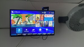 Un televisor montado en la pared que muestra una interfaz de servicio de streaming con diversas opciones de contenido.
