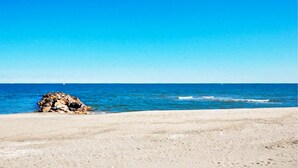 A beach with clear blue water, a rocky outcrop, and a sandy shore. - Lovely home in Le Barcarès with lake view (Le Barcarès)