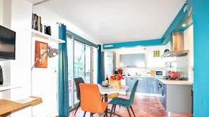A modern kitchen with a dining area, a TV, and a window with curtains. - Moderne villa piscine (Argelès-sur-Mer)