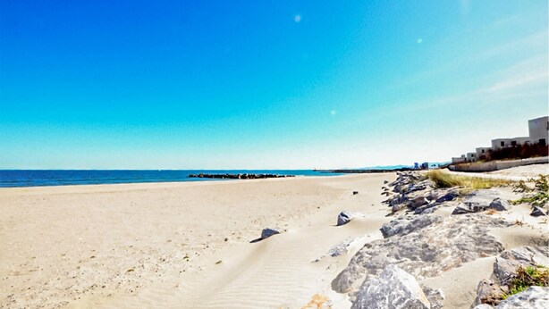 A beach with clear skies, a sandy shore, and a rocky outcrop with vegetation. - Moderne villa piscine (Argelès-sur-Mer)