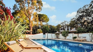 A swimming pool with lounge chairs, surrounded by trees and a white wall. - Moderne villa piscine (Argelès-sur-Mer)