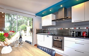 A modern kitchen with white cabinets, a black countertop, and a built-in oven. - Confortable maison piscine (Argelès-sur-Mer)
