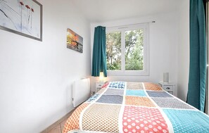 A bedroom with a bed, a window, a nightstand, and a lamp. - Paisible maison piscine (Argelès-sur-Mer)