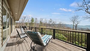 A wooden deck with two lounge chairs and a small table, overlooking a mountainous landscape. - Panoramic Blue Ridge Views | Expansive Deck, Fireplace, One-Level Living (Blowing Rock)