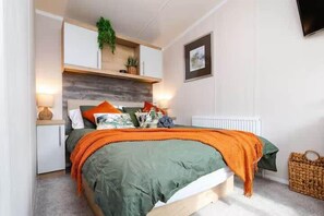 Une chambre à coucher comprenant un lit, des tables de chevet, un radiateur, une étagère murale avec des plantes et un tableau encadré.