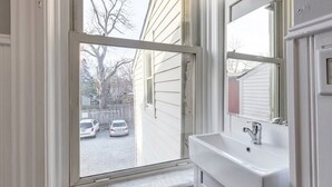 Ein Badezimmer mit Fenster, Waschbecken und Spiegel.