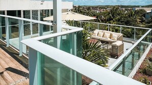 A rooftop terrace with a glass balustrade, a water feature, and a view of the surrounding landscape. - Flat com piscina privativa a beira mar (Ipojuca)