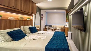 A modern hotel room with a bed, bedside tables, a desk, and a television. - Flat com piscina privativa a beira mar (Ipojuca)