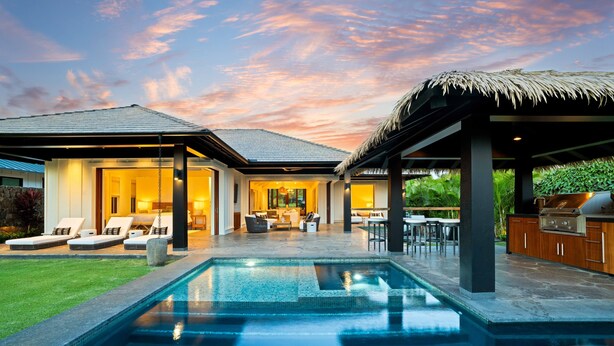Une maison moderne dotée d’une piscine, d’un espace salon extérieur et d’un coin barbecue.