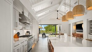 Une cuisine moderne avec des meubles blancs, un grand îlot central et des luminaires suspendus.