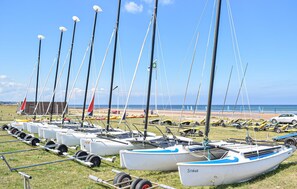 A row of sailboats docked on a grassy area with a beach and ocean in the background. - Maison à 100m de la plage (Bretteville-sur-Ay)