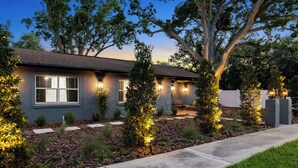 A modern house with a well-maintained garden, a paved driveway, and outdoor lighting. - Eternity Wellness Retreat Jacuzzi/Sauna/ColdPlunge (Tampa)