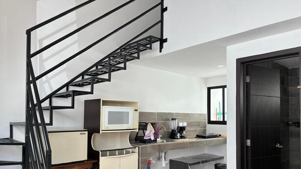 A compact kitchen with a microwave, coffee maker, and a water dispenser.