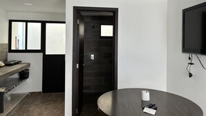 A modern kitchen with a black countertop, a round table, and a black door leading to a bathroom.