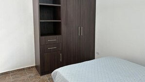 A bedroom with a bed, a wardrobe, and a tiled floor.