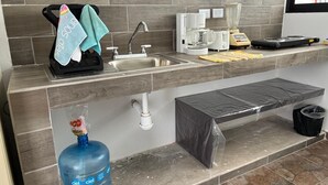 A kitchen with a sink, coffee maker, blender, and a water dispenser.