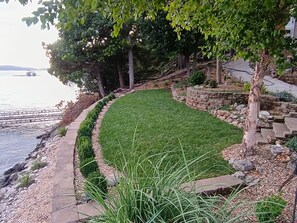 Ein angelegter Garten mit einem gewundenen Pfad, einem kleinen Wasserspielplatz und Blick auf ein Gewässer.