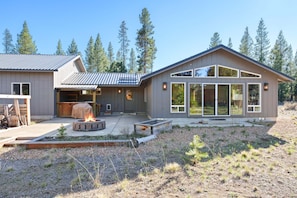 A modern house with a fire pit, large windows, and a deck.