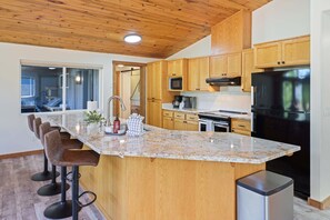 A kitchen with wooden cabinets, a granite countertop, a stainless steel refrigerator, and a built-in microwave.