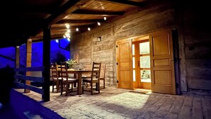 Eine rustikale Holzhütte mit Essbereich, einer Holztür und einem Backsteinboden.