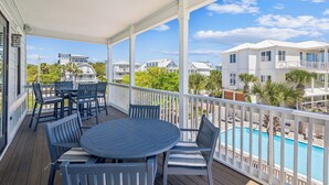Eine überdachte Terrasse im Freien mit Pool, Essbereich und weißen Geländern.