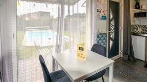 A dining area with a table and chairs, a view of a swimming pool, and a kitchen area with a microwave and refrigerator. - Amazing home in Taillades with outdoor swimming pool (Taillades)