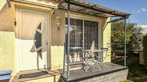 A house with a covered porch, a door, a window, and a small table with chairs. - Amazing home in Taillades with outdoor swimming pool (Taillades)