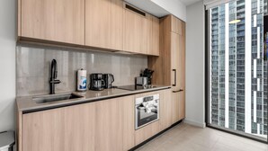 A modern kitchen with wooden cabinets, a built-in oven, a coffee maker, and a window with a city view. - Luxury High-Rise 1BR in Downtown Miami (Miami)