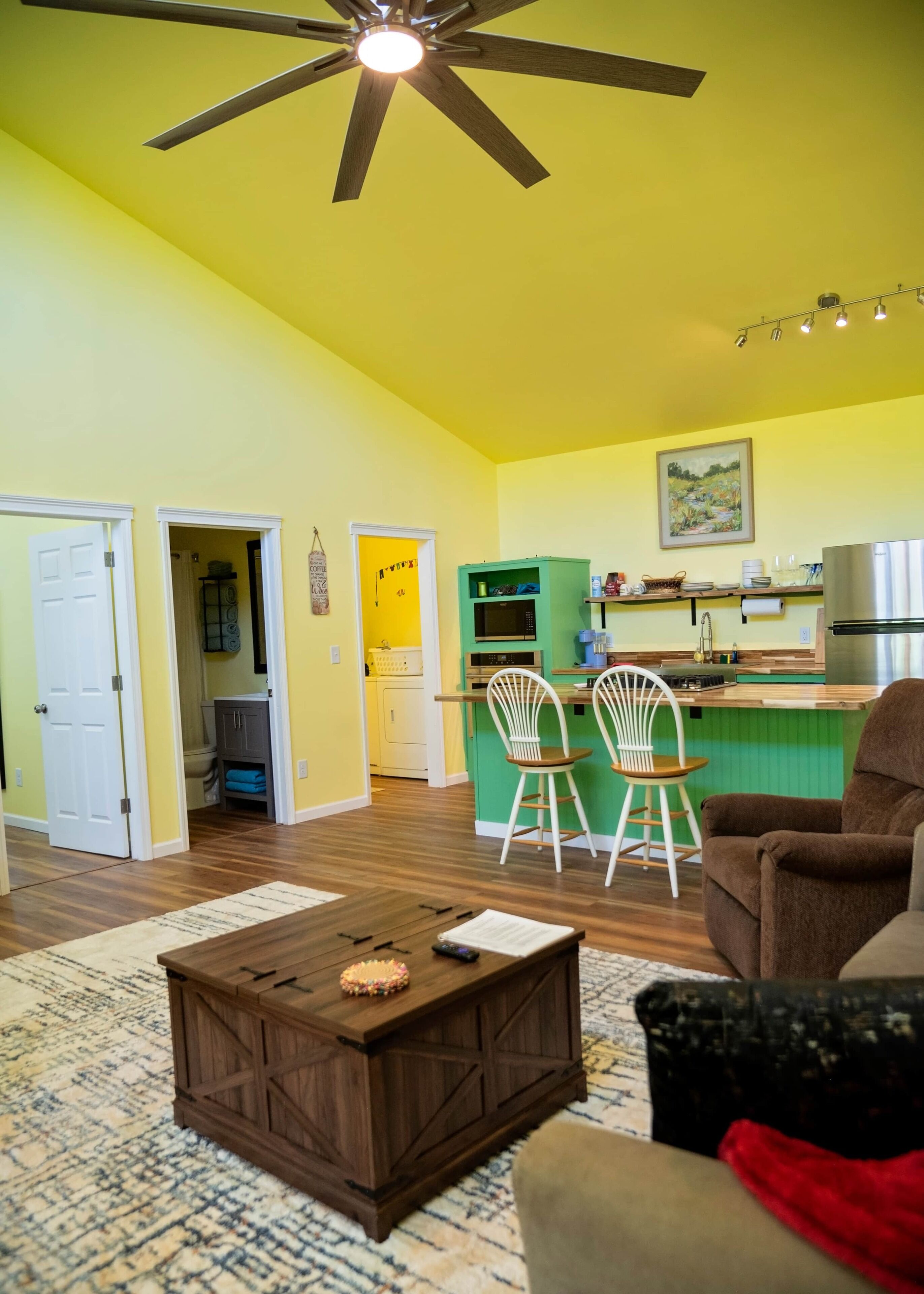 Un salon avec une table basse, un fauteuil marron et un ventilateur de plafond.