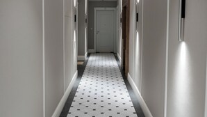 En hall med ett mönstrat golv, vita väggar och dörrar.