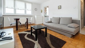 Una sala de estar moderna con un sofá, una mesa de comedor, sillas, una mesita de centro y una alfombra.