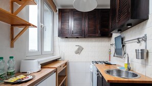 Una cocina con armarios de madera, una encimera blanca, un fregadero, una estufa y un ventanal.