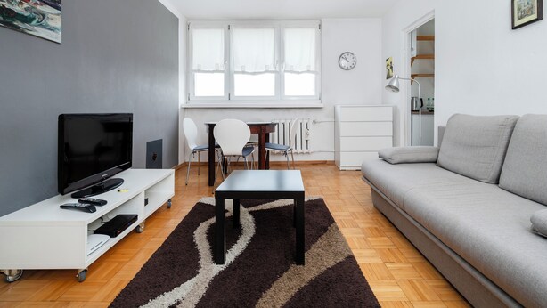 Una sala de estar moderna con televisor, sofá y comedor.