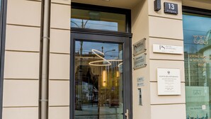 Ein Gebäudeeingang mit einer Glastür, einer darüber befindlichen Beschilderung mit dem Schriftzug 'KULINARN' und mehreren an der Wand angebrachten Tafeln.