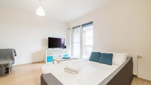 Moderni hotellihuone, jossa on suuri sänky, taulutelevisio, työpöytä ja tuoli.