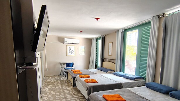 Ein Hotelzimmer mit zwei Betten, einem Schreibtisch, einem Fernseher und einem gemusterten Boden.