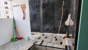 Ein Zimmer mit Fliesenboden, einer Wand aus schwarzem Marmor und einem Fenster mit Gitterstäben.