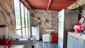 Eine Küche mit Gaskochfeld, Kühlschrank, Spüle und einem Fenster.