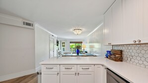 A modern kitchen with white cabinetry, a central island, and a hexagonal tile backsplash. - New to VRBO, Oceanwalk, Near Beach, Outdoor and Indoor Pool, Hot Tub (Hilton Head Island)