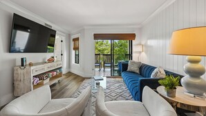 A living room with a TV, sofa, chairs, a coffee table, and a view of the outdoors. - New to VRBO, Oceanwalk, Near Beach, Outdoor and Indoor Pool, Hot Tub (Hilton Head Island)