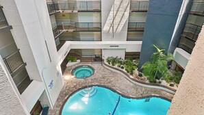 A multi-level indoor pool area with a central pool and a smaller circular pool, surrounded by balconies and indoor plants. - New to VRBO, Oceanwalk, Near Beach, Outdoor and Indoor Pool, Hot Tub (Hilton Head Island)