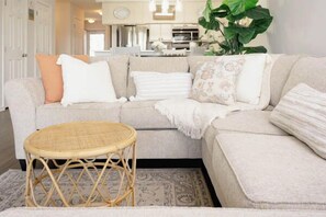 A living room with a sofa, a round wicker table, and a large plant. - Tee Time Retreat- Pool Access + Premier Golf (Myrtle Beach)