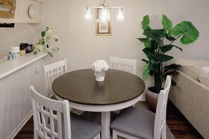 A dining area with a round table, white chairs, a potted plant, and a light fixture. - Tee Time Retreat- Pool Access + Premier Golf (Myrtle Beach)