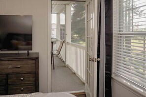 A room with a bed, a dresser, a TV, and a door leading to a balcony with a railing. - Tee Time Retreat- Pool Access + Premier Golf (Myrtle Beach)